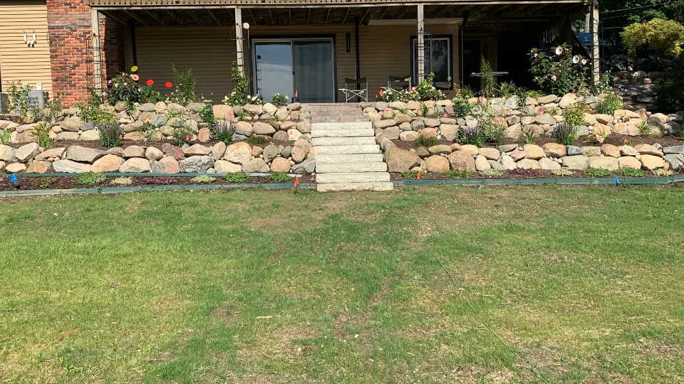 Large Boulder Retaining Wall With Built-In Flower Beds and Stairs